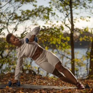 Person exercising outdoors with dumbbells near lake.